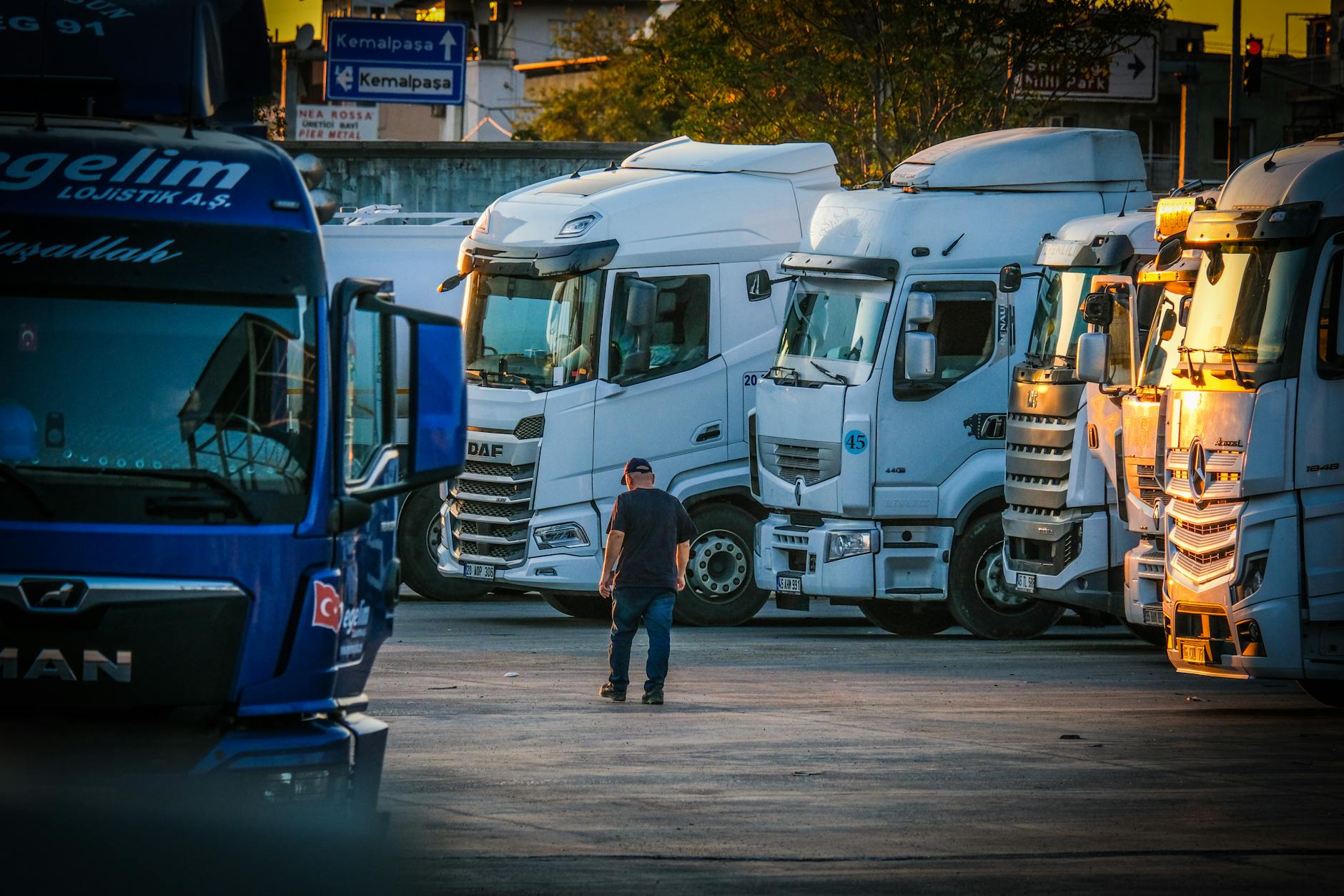 Kierowca pieszo między zaparkowanymi ciężarówkami o zachodzie słońca