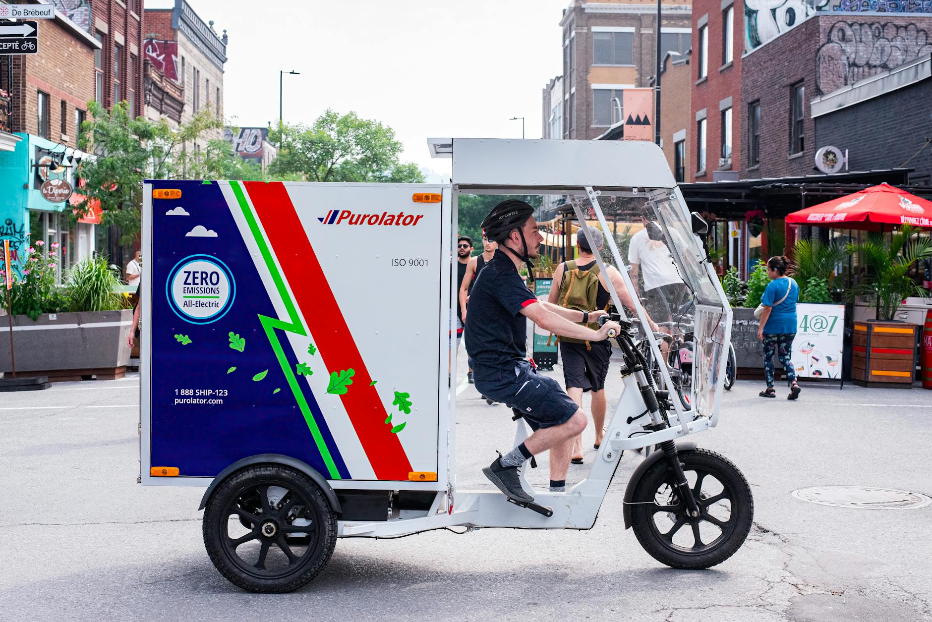 Kuriera na elektrycznym trójkołowym rowerze dostawczym w centrum miasta