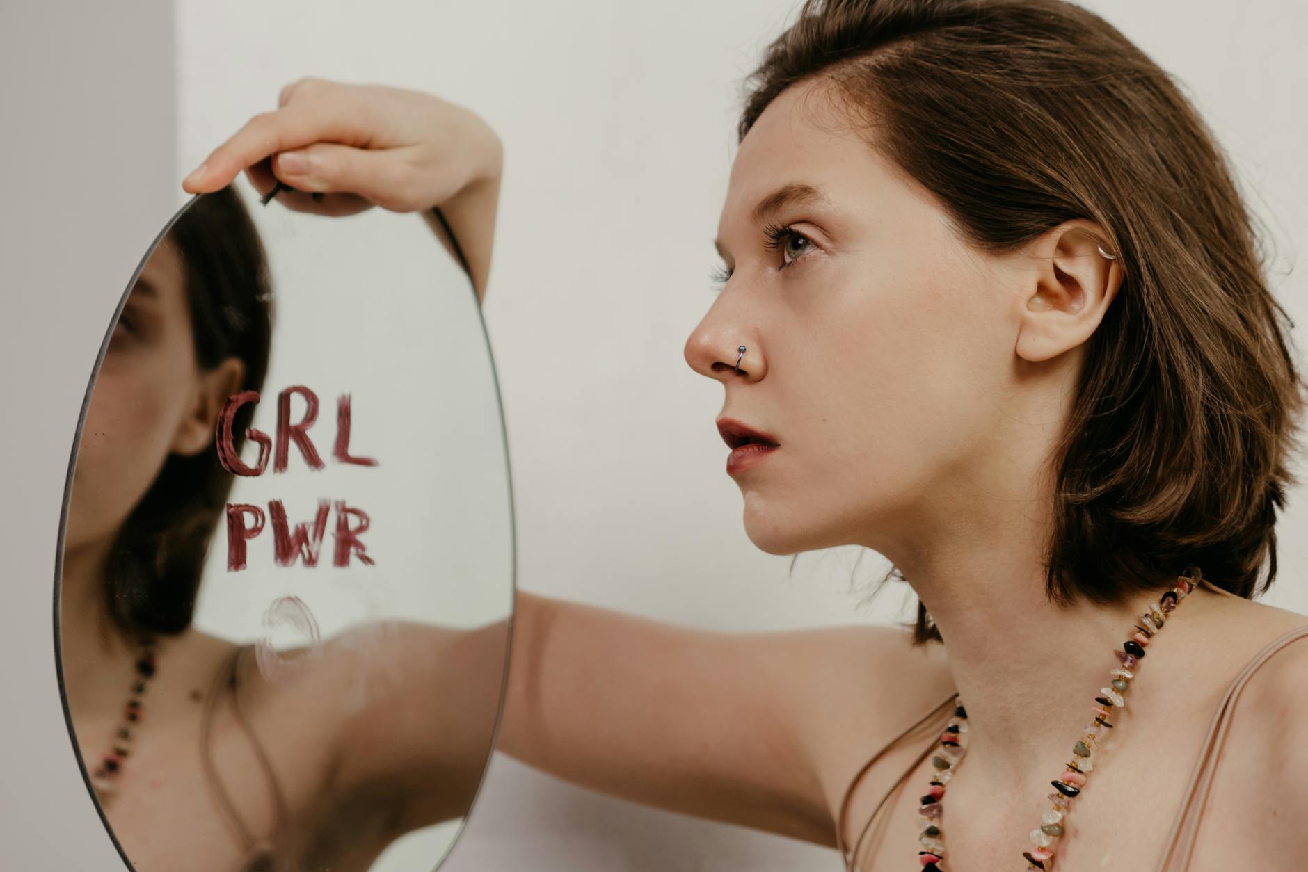 Młoda kobieta patrzy w lustro z napisem GRL PWR
