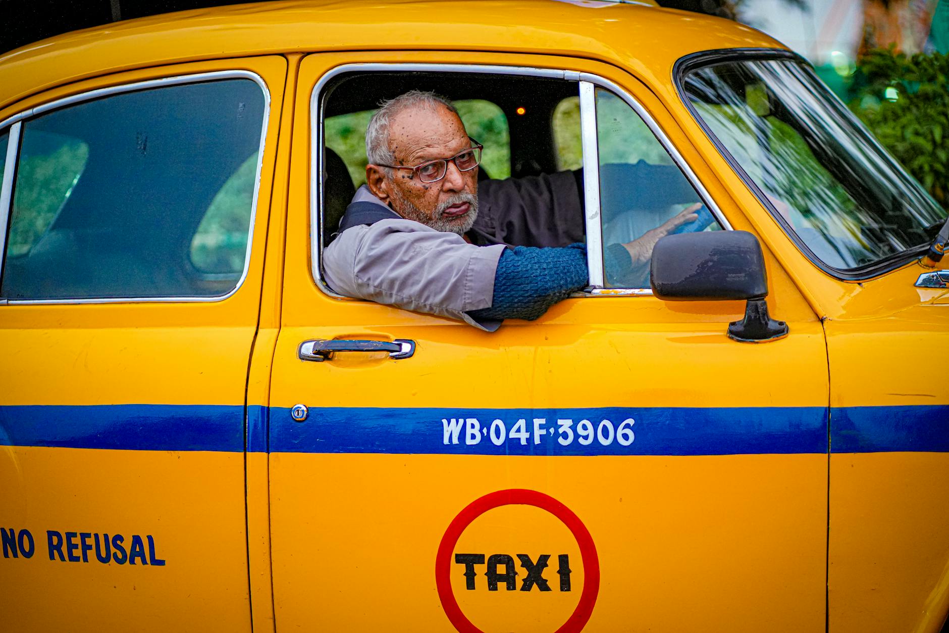 Starszy kierowca prowadzi żółtą taksówkę na ruchliwej ulicy miasta