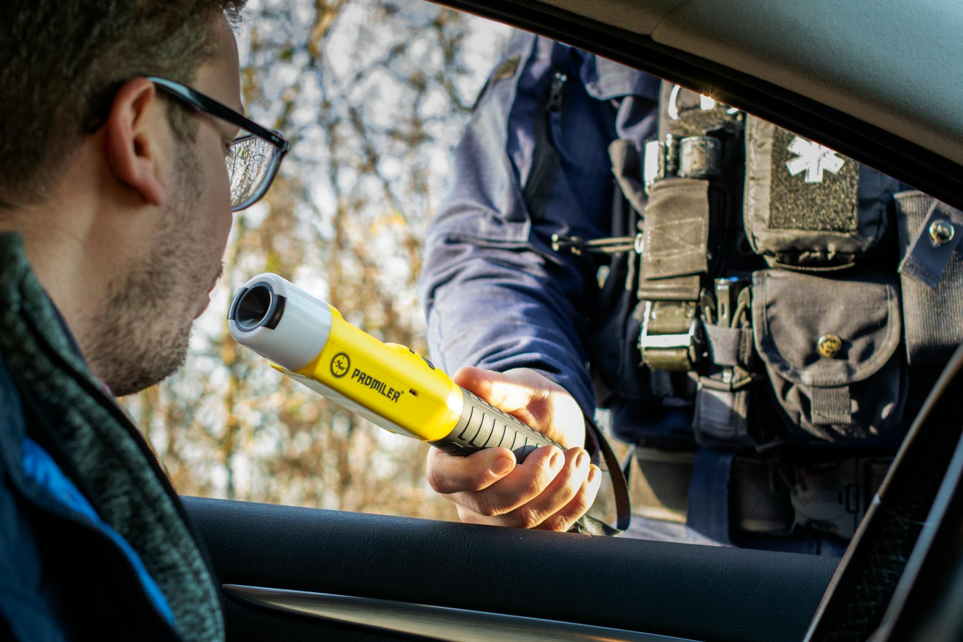 Policjant wykonuje kierowcy badanie alkomatem podczas kontroli drogowej