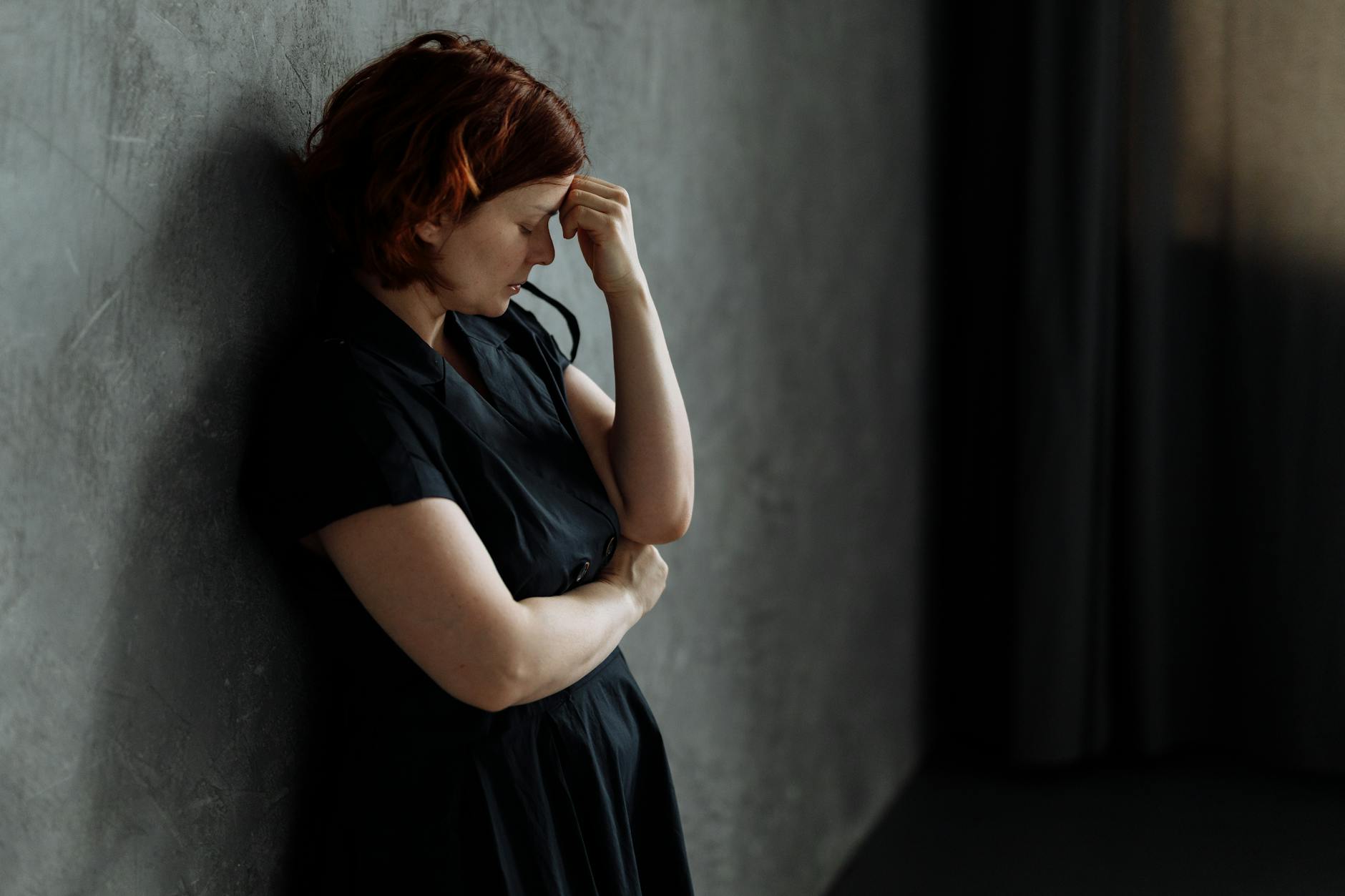Jak trauma po wypadku może wpływać na pamięć, koncentrację i funkcjonowanie w codziennym życiu Zestresowana kobieta opierająca się o betonową ścianę z zamkniętymi oczami