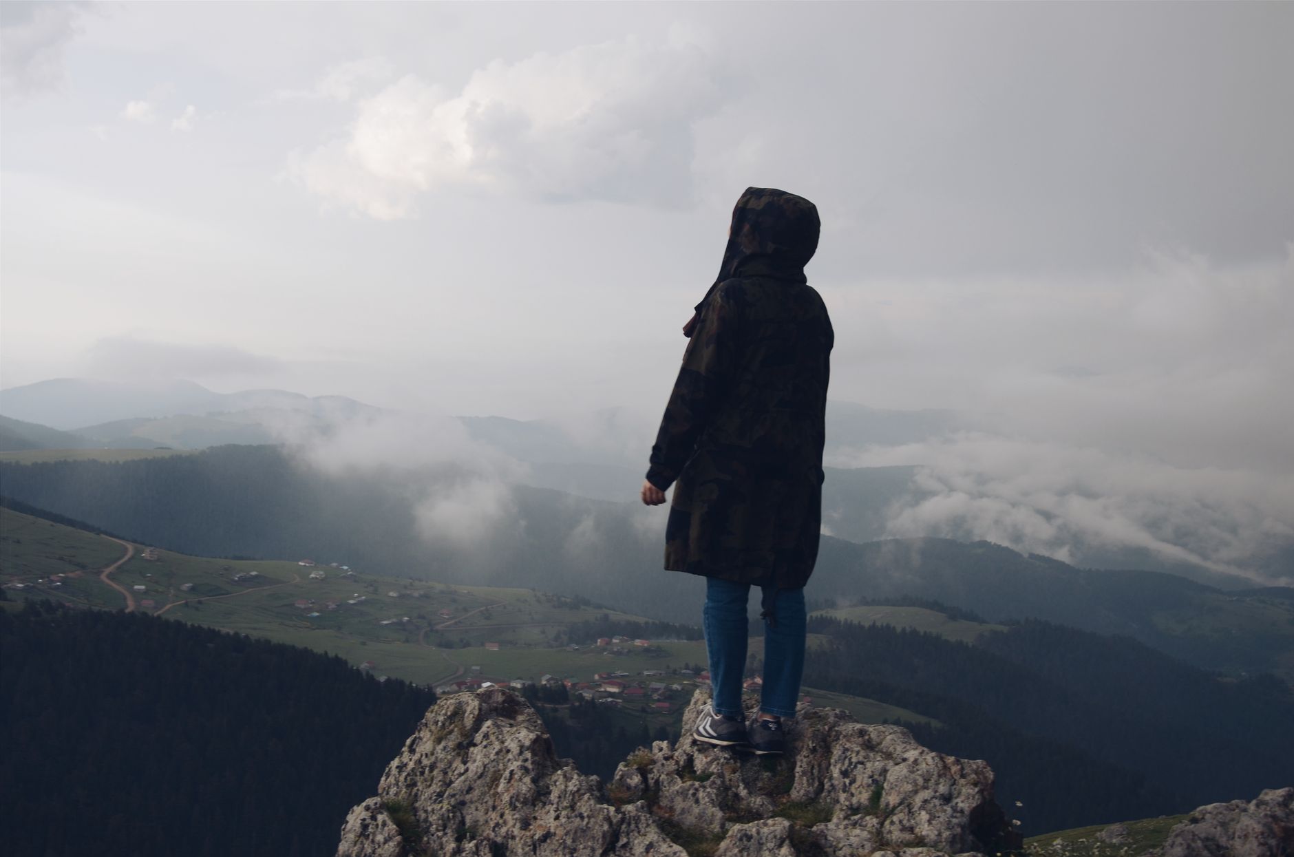 Sylwetka osoby na skalnej krawędzi z widokiem na mglistą górską panoramę